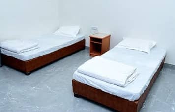 Clean twin room with two single beds, white linen and a bedside table